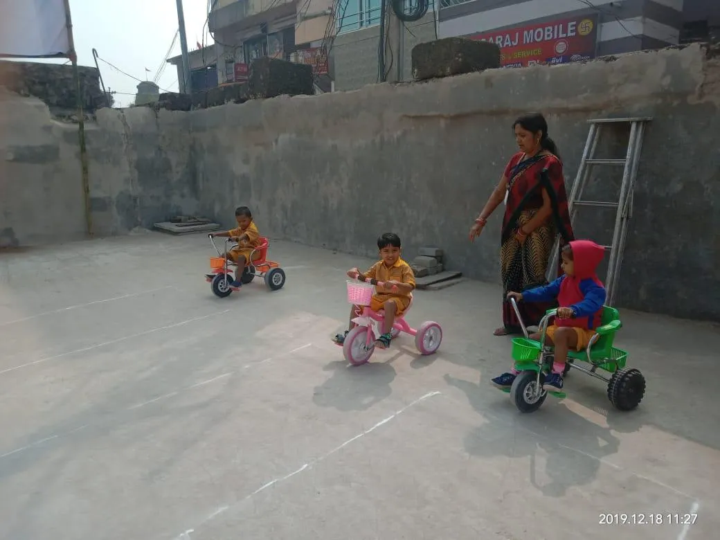 Tricycle play with a teacher nearby
