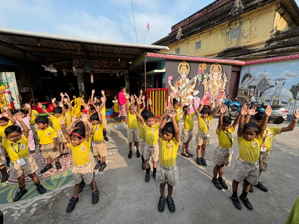 Kids Planet children raising their arms together during an outdoor group activity