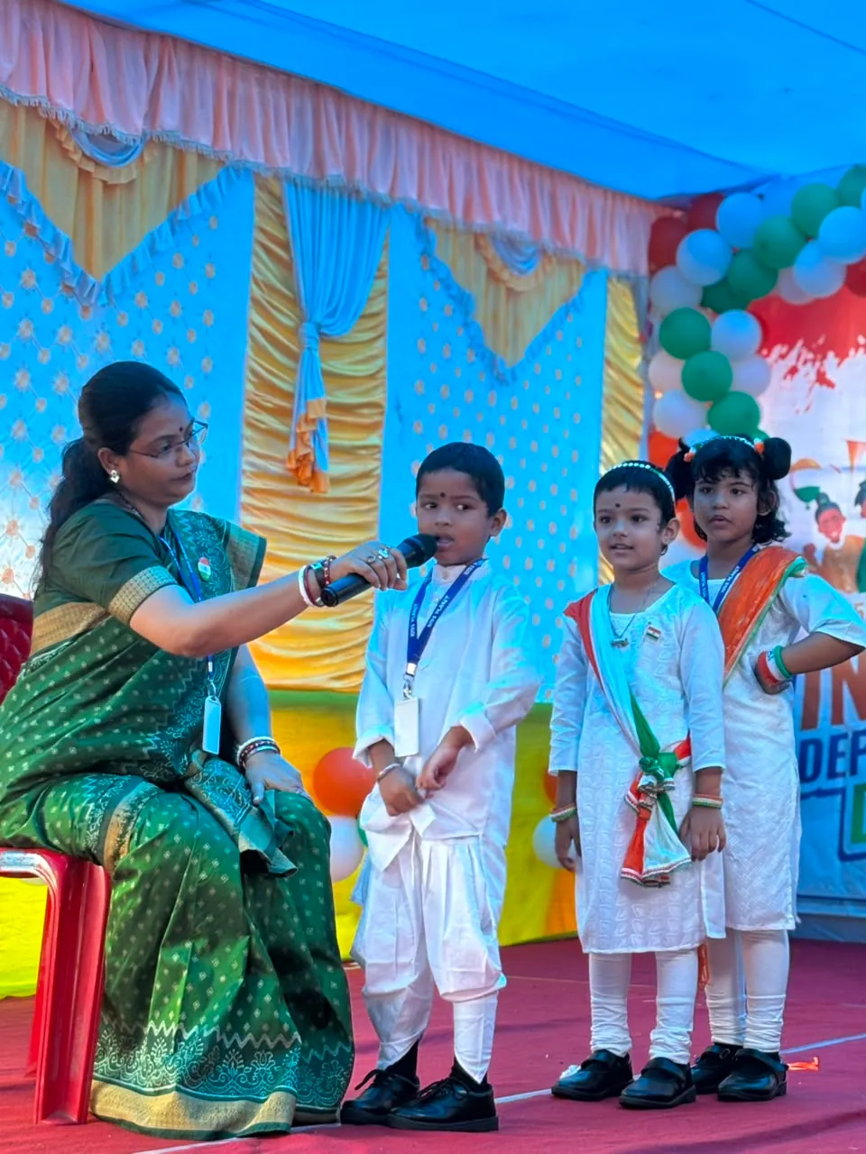 A teacher holding a microphone for a child during a Kids Planet school celebration